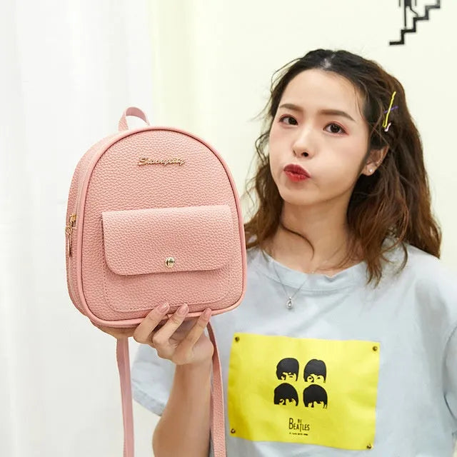 Compact black PU leather women's shoulder backpack worn crossbody, showing zipper closure and simple design.