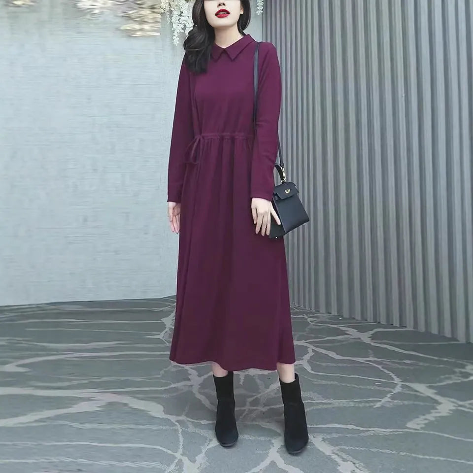 A woman wearing a solid purplish-red long-sleeve maxi dress with extra-long sleeves, suitable for autumn and winter.