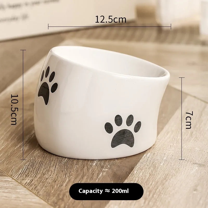 Ceramic cat food bowl with high foot base in a cat's paw print design