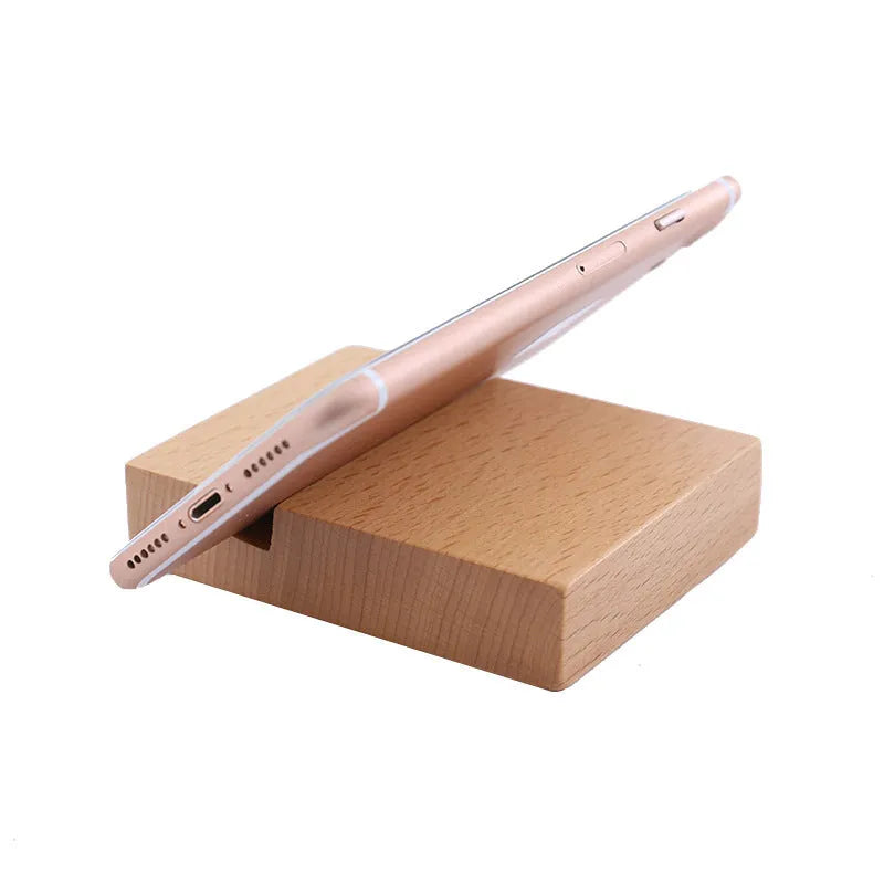Solid beech wood mobile phone stand with a resin cow figurine and a slot for holding coins on a wooden desk.