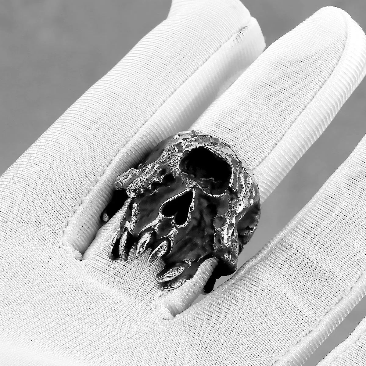 A silver-toned alloy ring featuring a detailed one-eyed skull design on a black background.