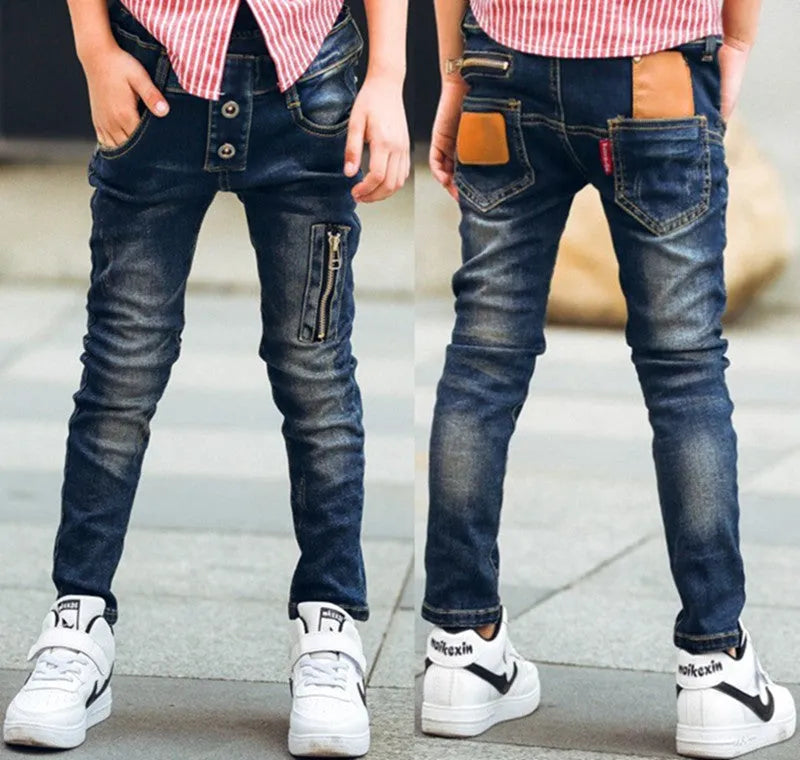 Boy wearing dark blue stretch denim jeans with zipper pockets, size chart shown