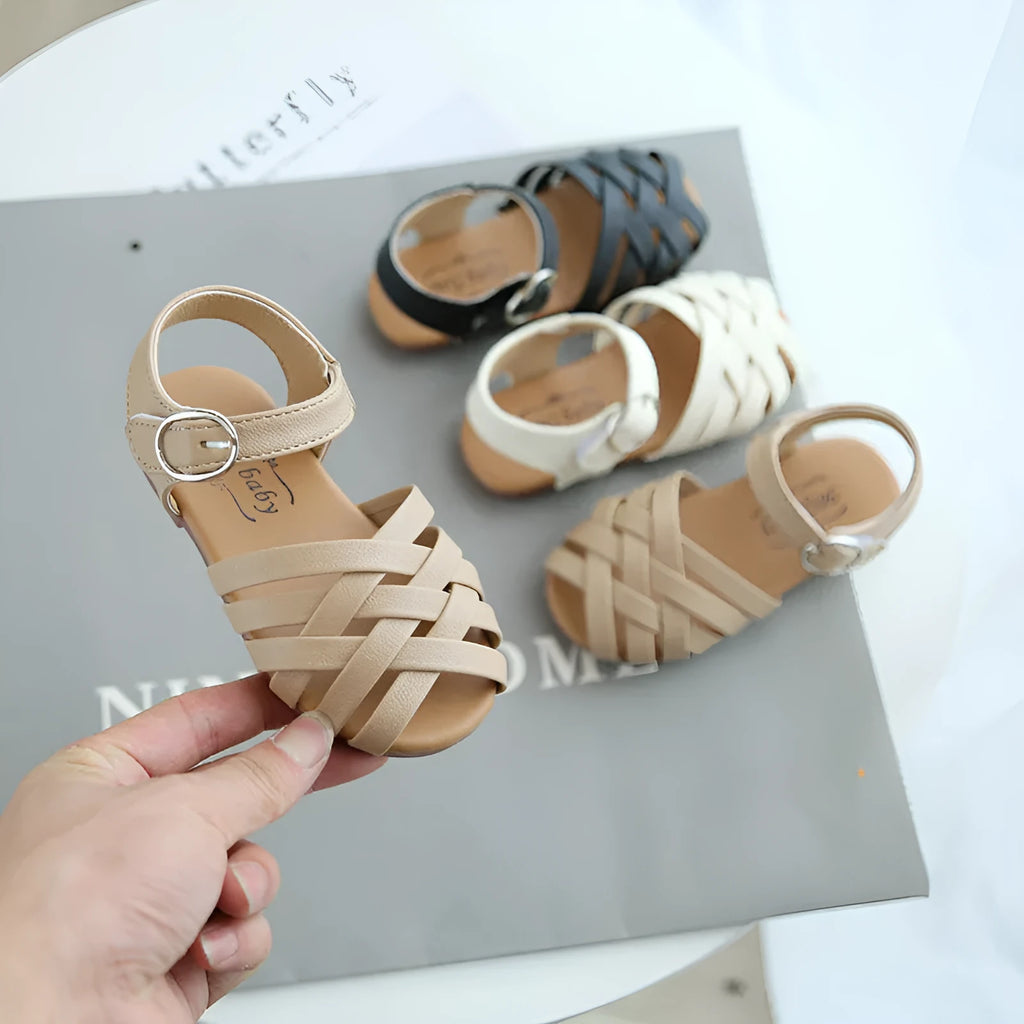 Child wearing white buckle toe soft sole woven sandals on a sunny day