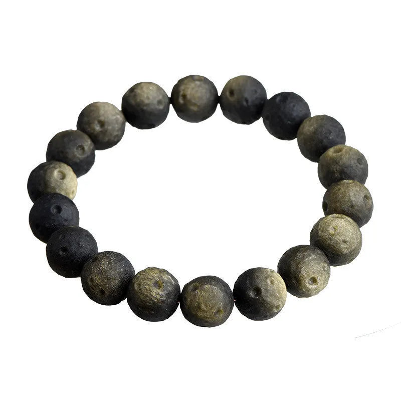 Obsidian crater ball bracelet on a wrist, showing ground stone texture and bead size.