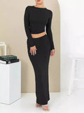 Women's black slim fit two-piece suit with exposed navel top and long skirt.