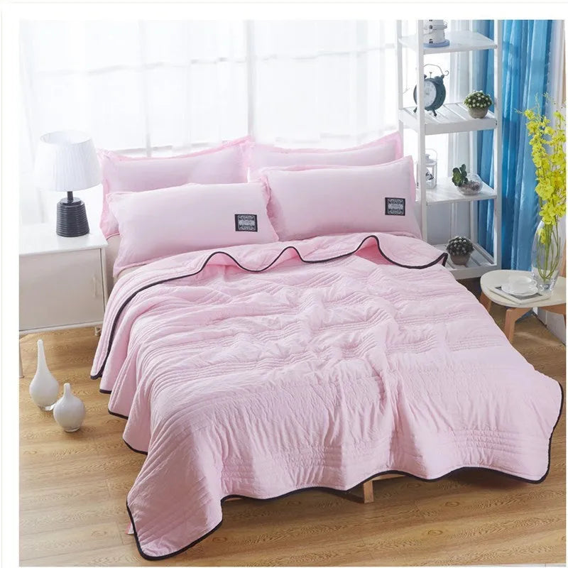 Lightweight seersucker summer quilt in various colours on a bed
