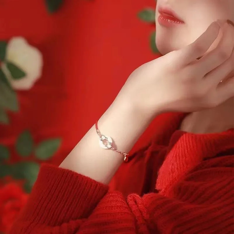 Festive Koi women's bracelet with red rope and peace buckle closure on a wrist.