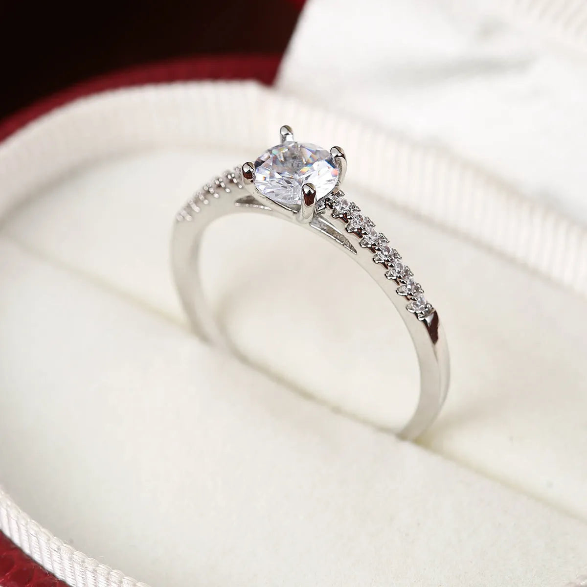A hexagonal geometric ring with a zircon stone, shown in a gun black and rose red electroplated finish on a finger.