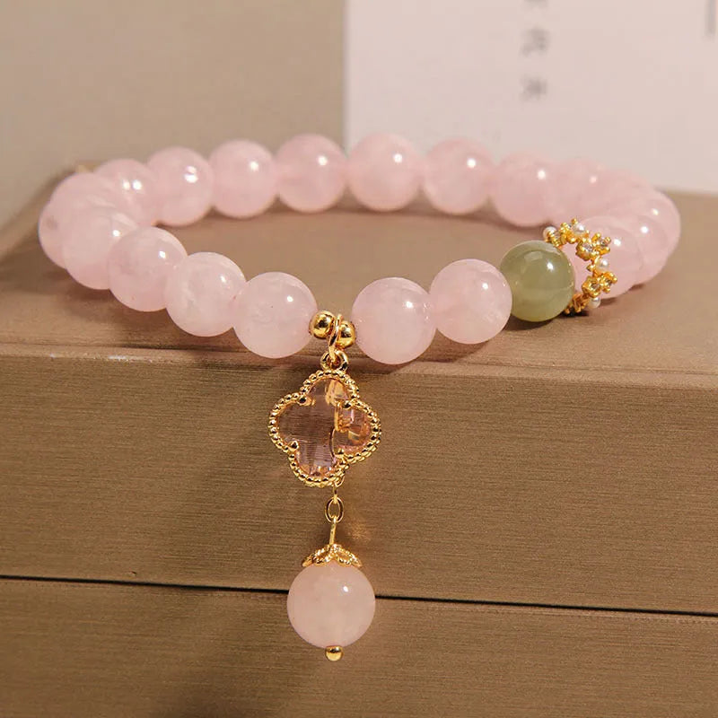 Pink crystal women's bracelet with four-leaf clover pendant charm and rhinestone decoration.