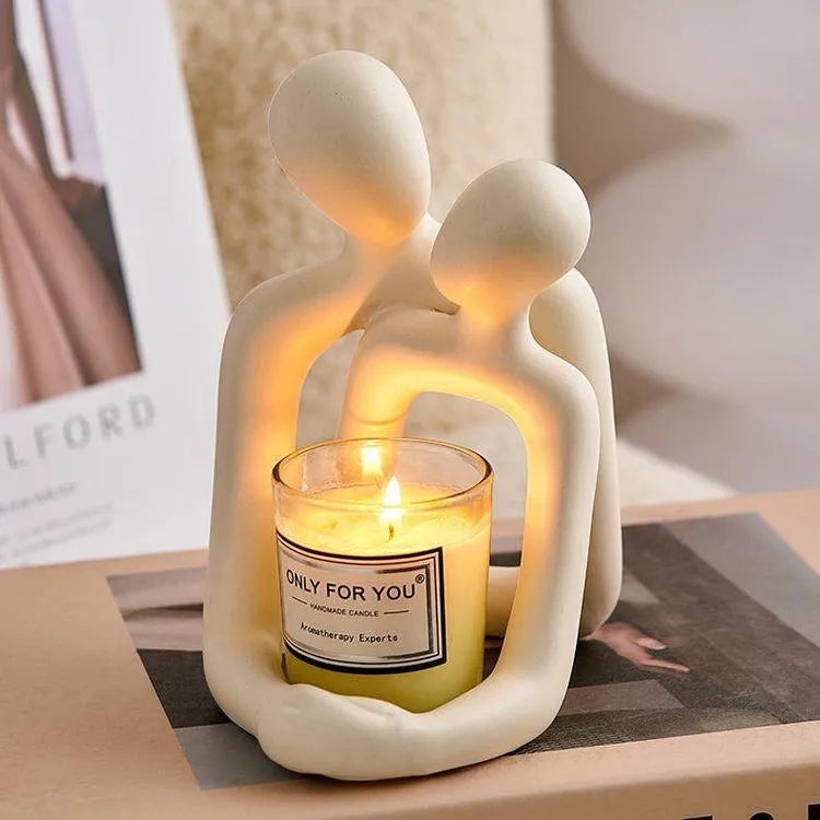 Modern minimalist resin statue of a couple in milky white or gold finish on a wooden surface.