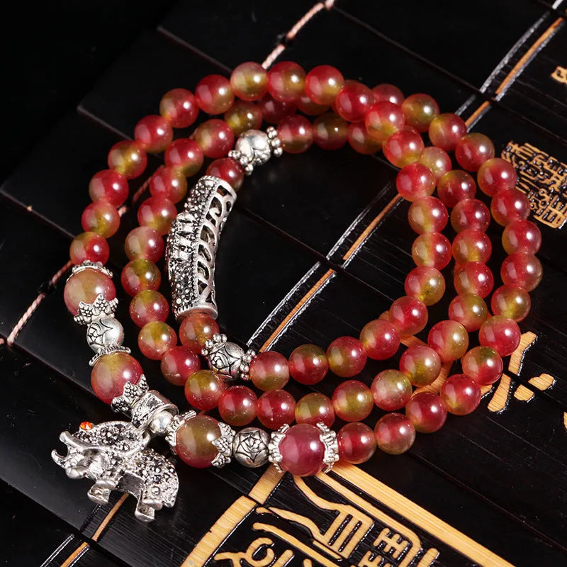 Handmade natural watermelon crystal bracelet with a Chinese knot, showing geometric beads in elephant style.