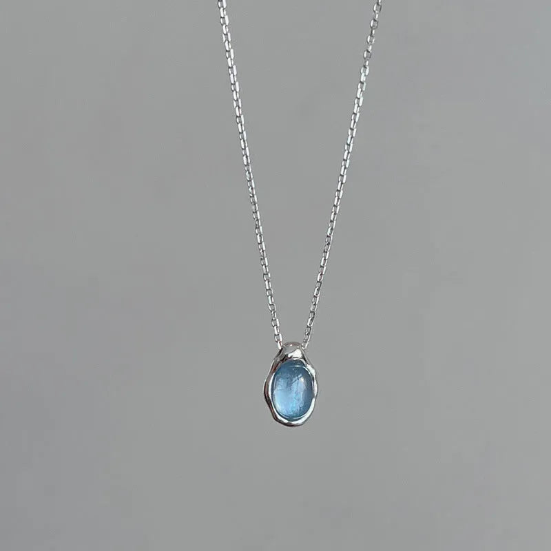 Close-up of a navy blue geometric water drop pendant on an adjustable silver-tone chain
