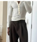 A man's cream-coloured long-sleeve henley top with a ribbed texture and three-button placket.