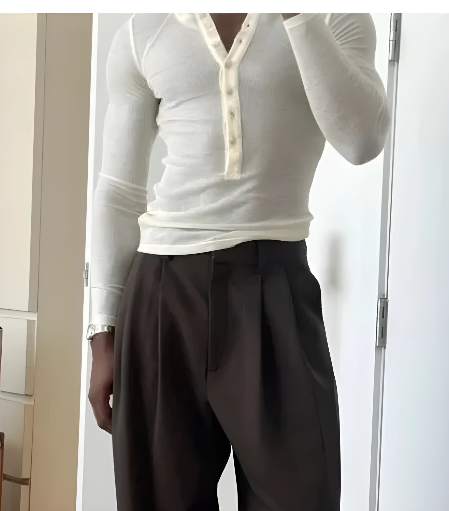 A man's cream-coloured long-sleeve henley top with a ribbed texture and three-button placket.
