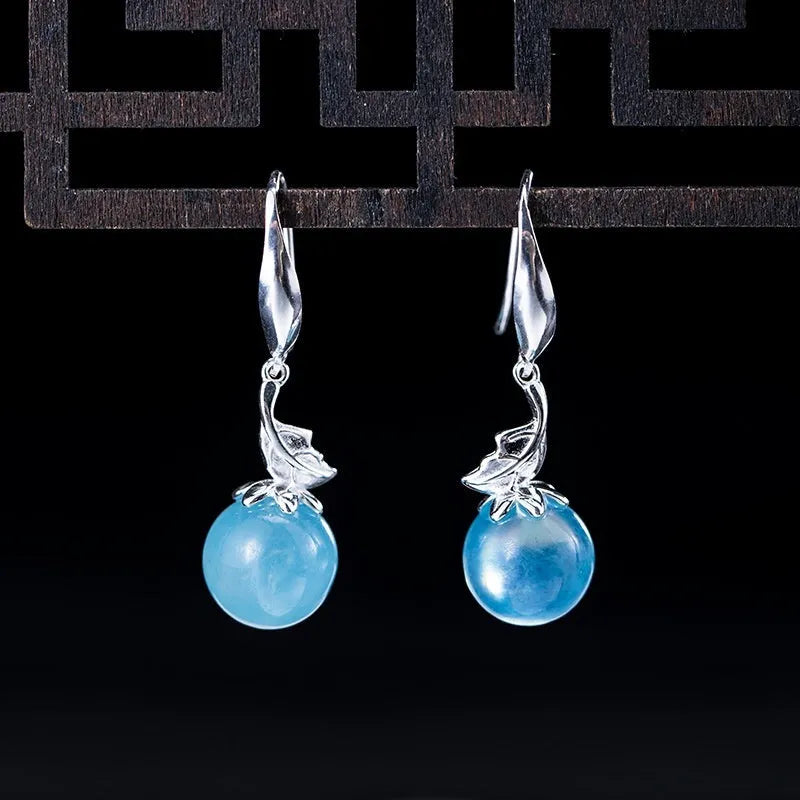 A pair of vintage-style silver earrings featuring aquamarine leaf and four-petal flower designs.