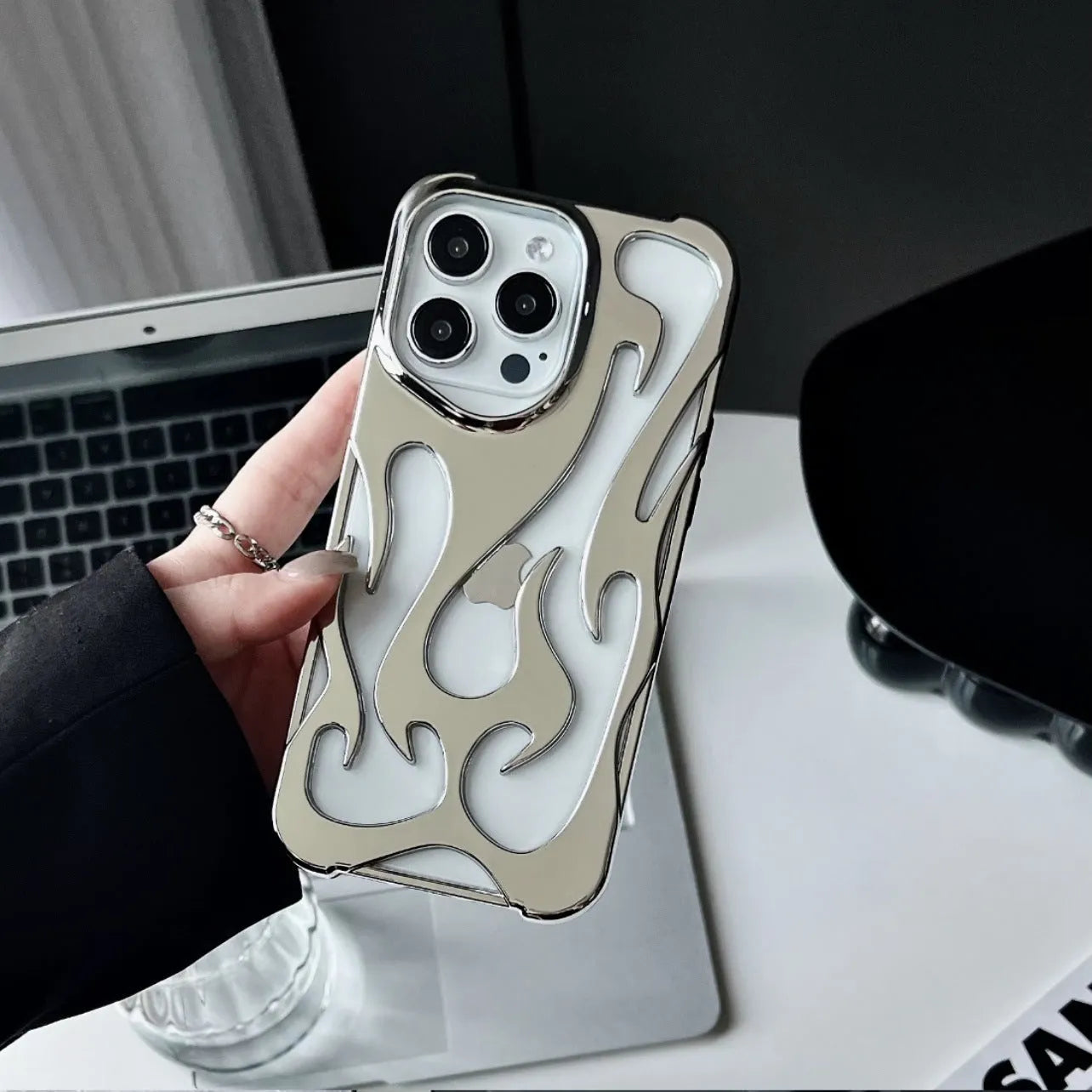Electroplated hollow flame pattern iPhone case in silver, showing detailed cut-outs and metallic finish on a phone.