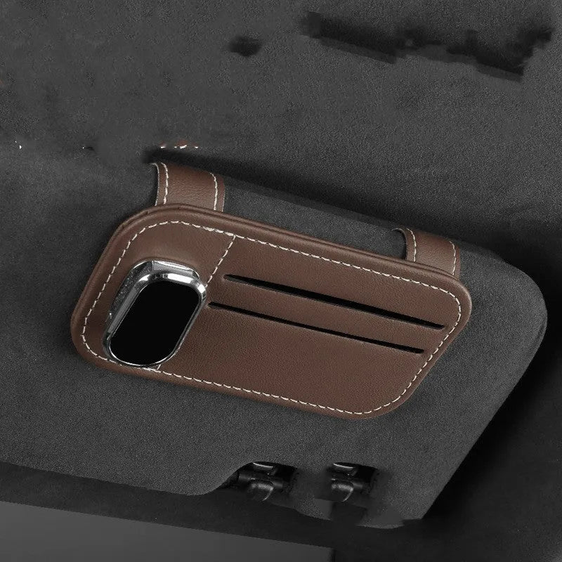 Beige cowhide automotive sun visor clip holding cards and sunglasses.