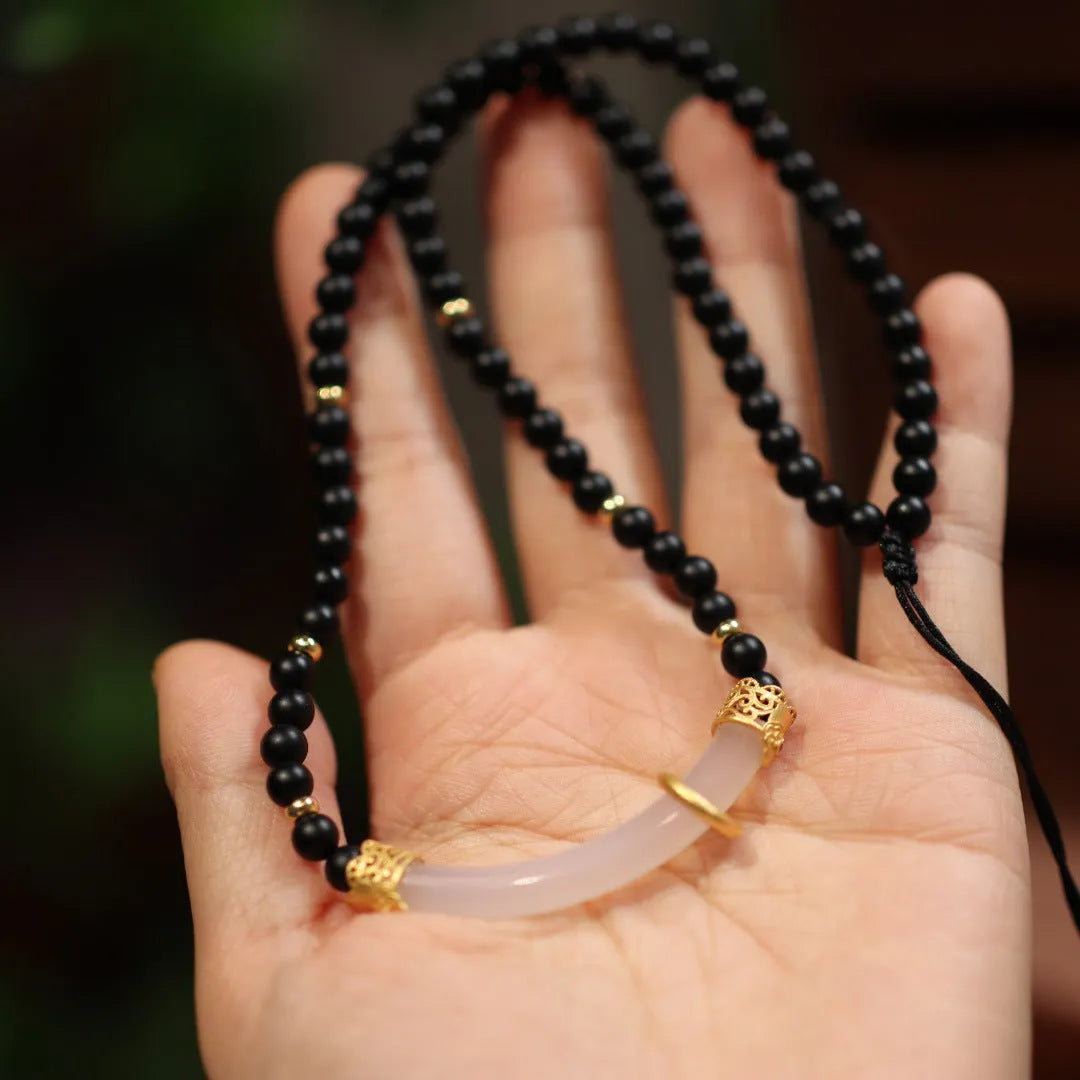 Close-up of a Chinese style U-shaped necklace with a frosted black agate and white chalcedony pendant on a silver ball bead chain.