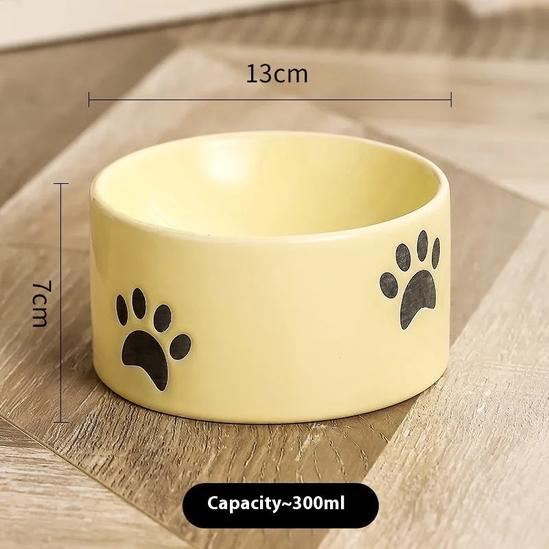 Ceramic cat food bowl with high foot base in a cat's paw print design