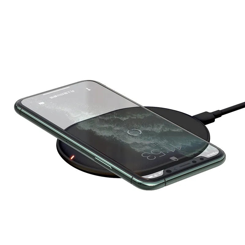 Baseus Rough 15W wireless charging pad in black on a table next to a mobile phone.
