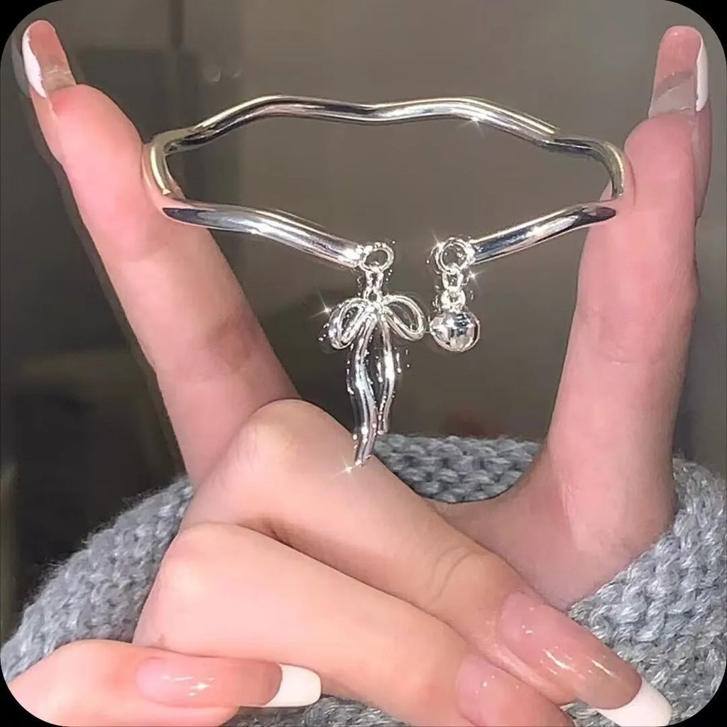 Silver adjustable bracelet with a large bow charm on a model's wrist, showing the sliding clasp.