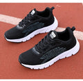 Women's black and white low-top running sneakers with cross strap design and MD soles