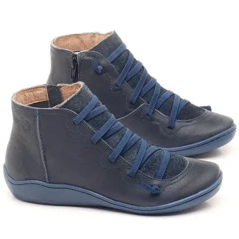 Women's black flat casual ankle boot with round toe and low wedge heel on a wooden floor.