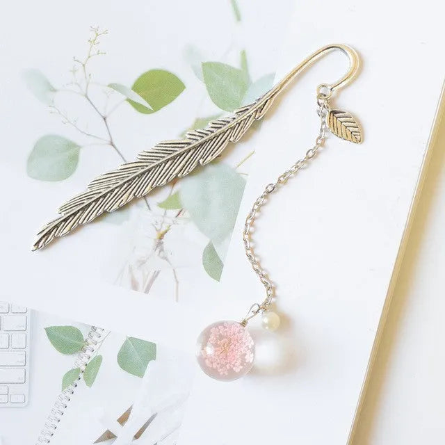 Close-up of a metal bookmark with a dried dandelion flower sealed inside, showing its 12cm length and slim profile.