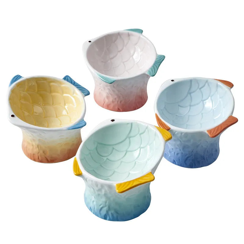 Blue ceramic fish-shaped cat bowl with tilted design and non-slip base on a wooden surface