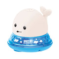Grey and white cartoon whale bath toy spraying water with LED lights illuminated on water surface.