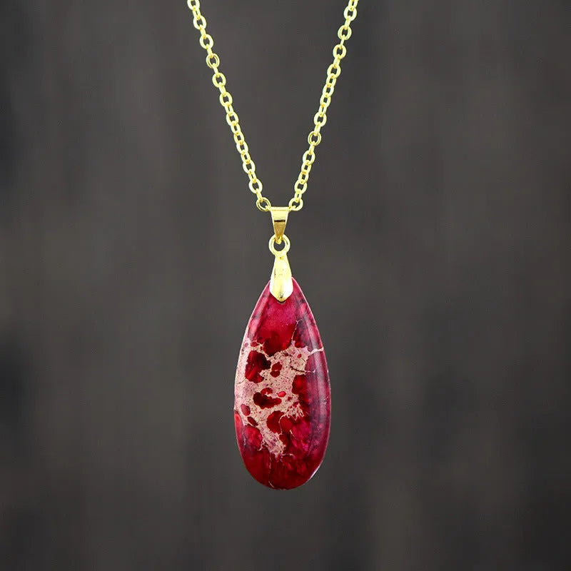 Close-up of an Emperor Stone necklace with a teardrop-shaped green jade pendant on a gold-plated chain, showing natural stone veining.