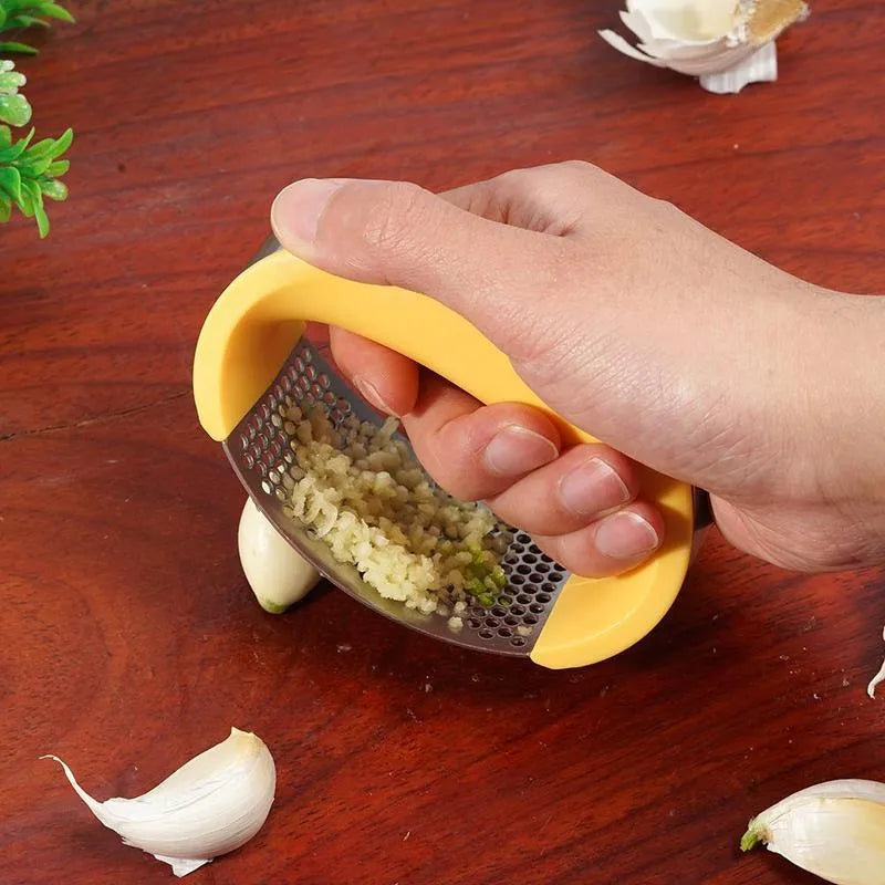 Stainless steel garlic press with ergonomic handle in assorted colours on a kitchen counter.