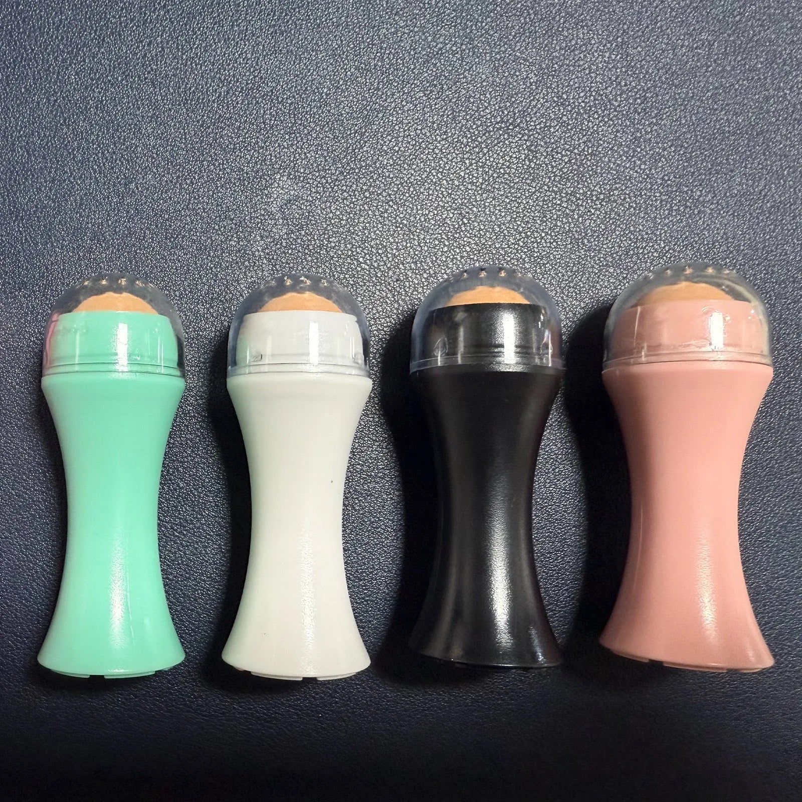 Volcanic stone facial roller for oily skin control in black, green, pink, and white colour options.