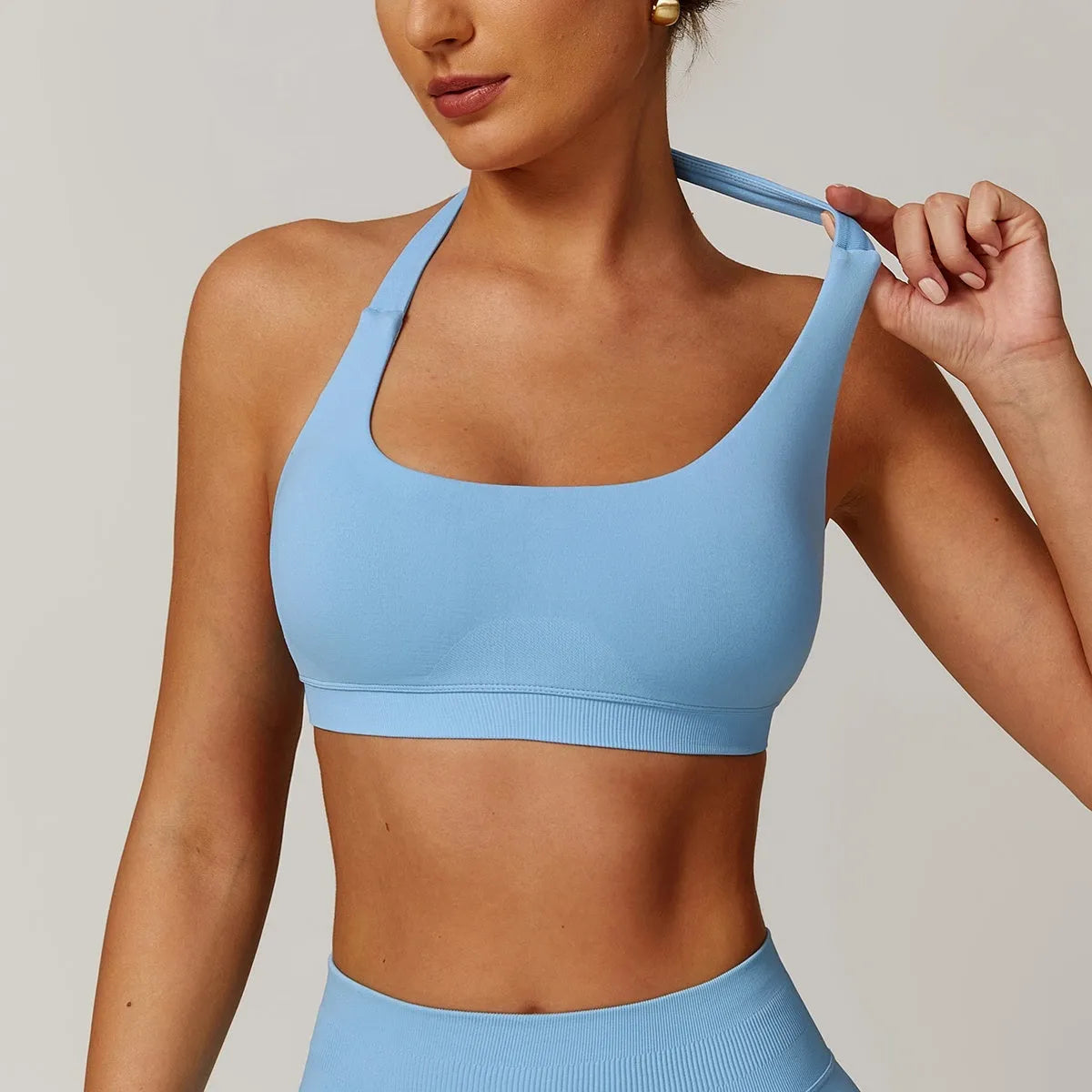 Women's halter-neck yoga bra in plum purple, showing hollow-back design and removable padding on a neutral background.