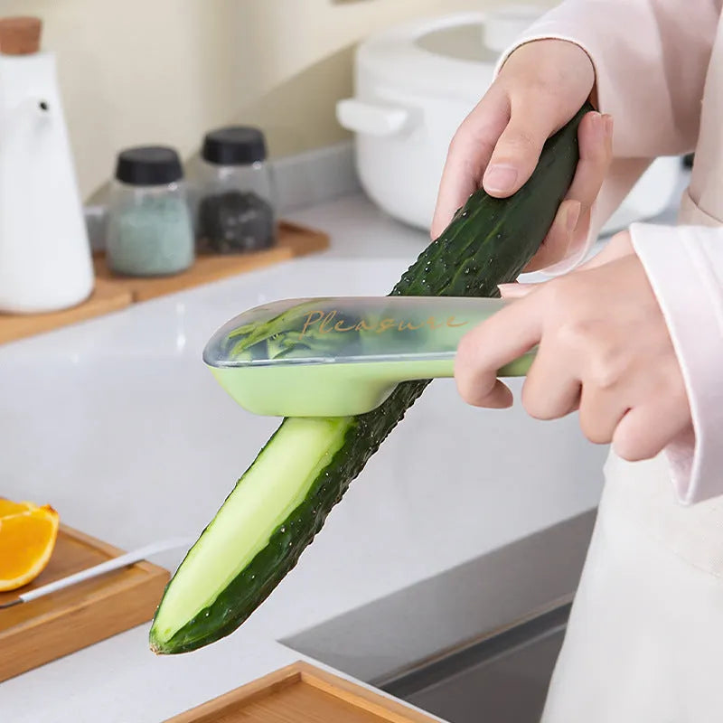 Dark green kitchen peeler with storage tube, non-slip handle, and stainless steel blade on a kitchen counter.