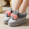 A pair of high-heel winter slippers with a plush fabric upper and a thick TPR sole.