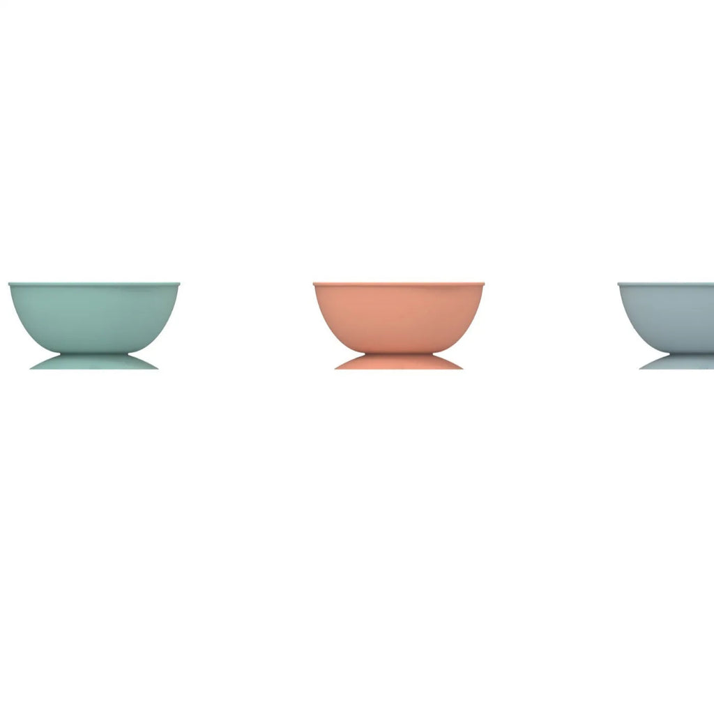 Cyan silicone dog bowl with textured slow-feed surface and a suction cup base on a kitchen floor.