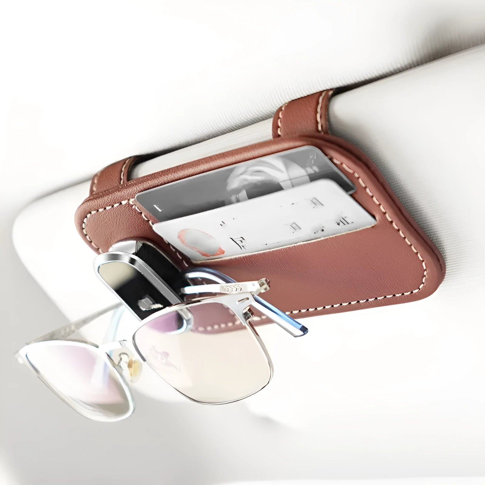 Beige cowhide automotive sun visor clip holding cards and sunglasses.