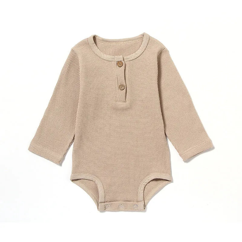 Infant wearing a beige waffle cotton long sleeve romper climbing suit