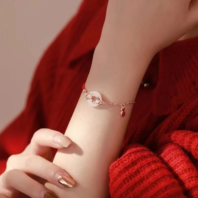Festive Koi women's bracelet with red rope and peace buckle closure on a wrist.