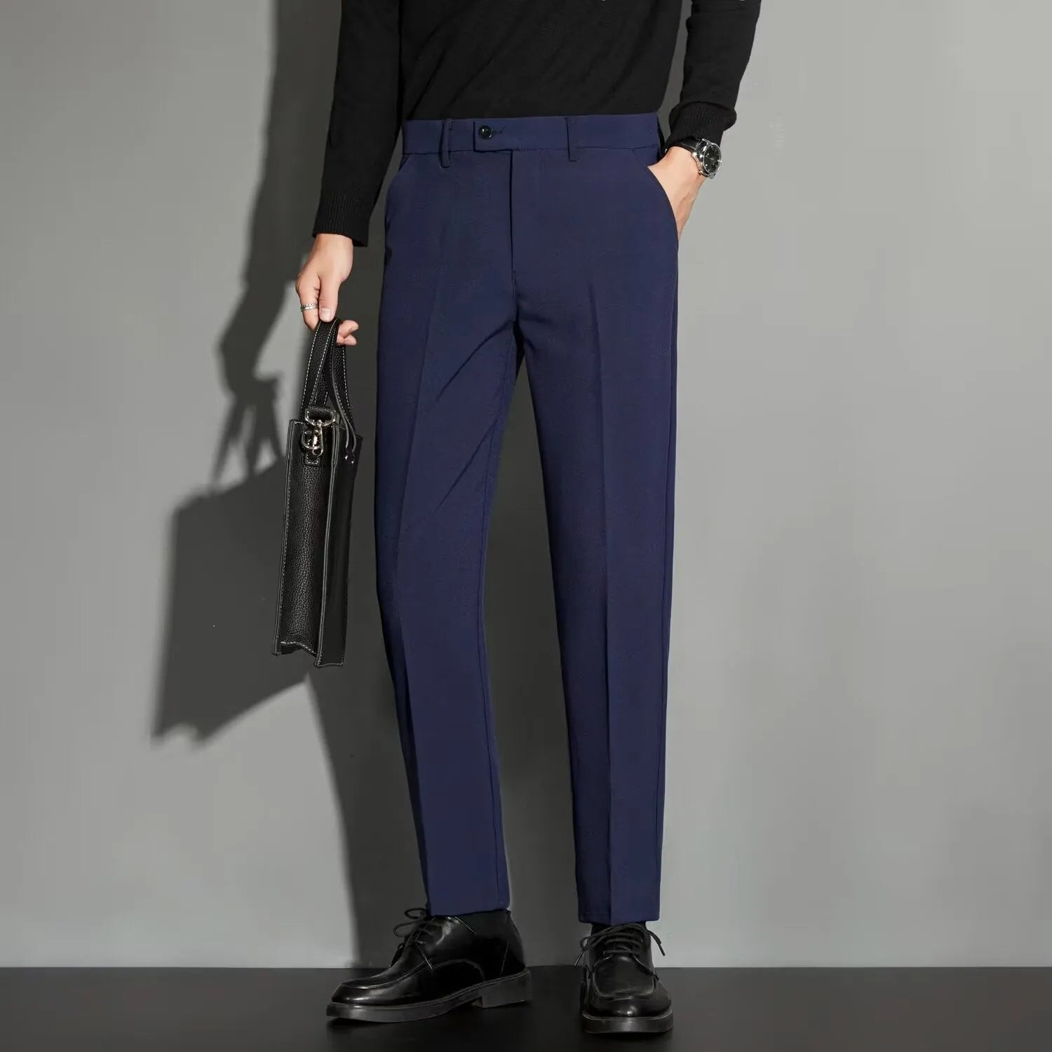 Men's straight-leg ankle-length suit trousers in a light colour showing drape and fit.