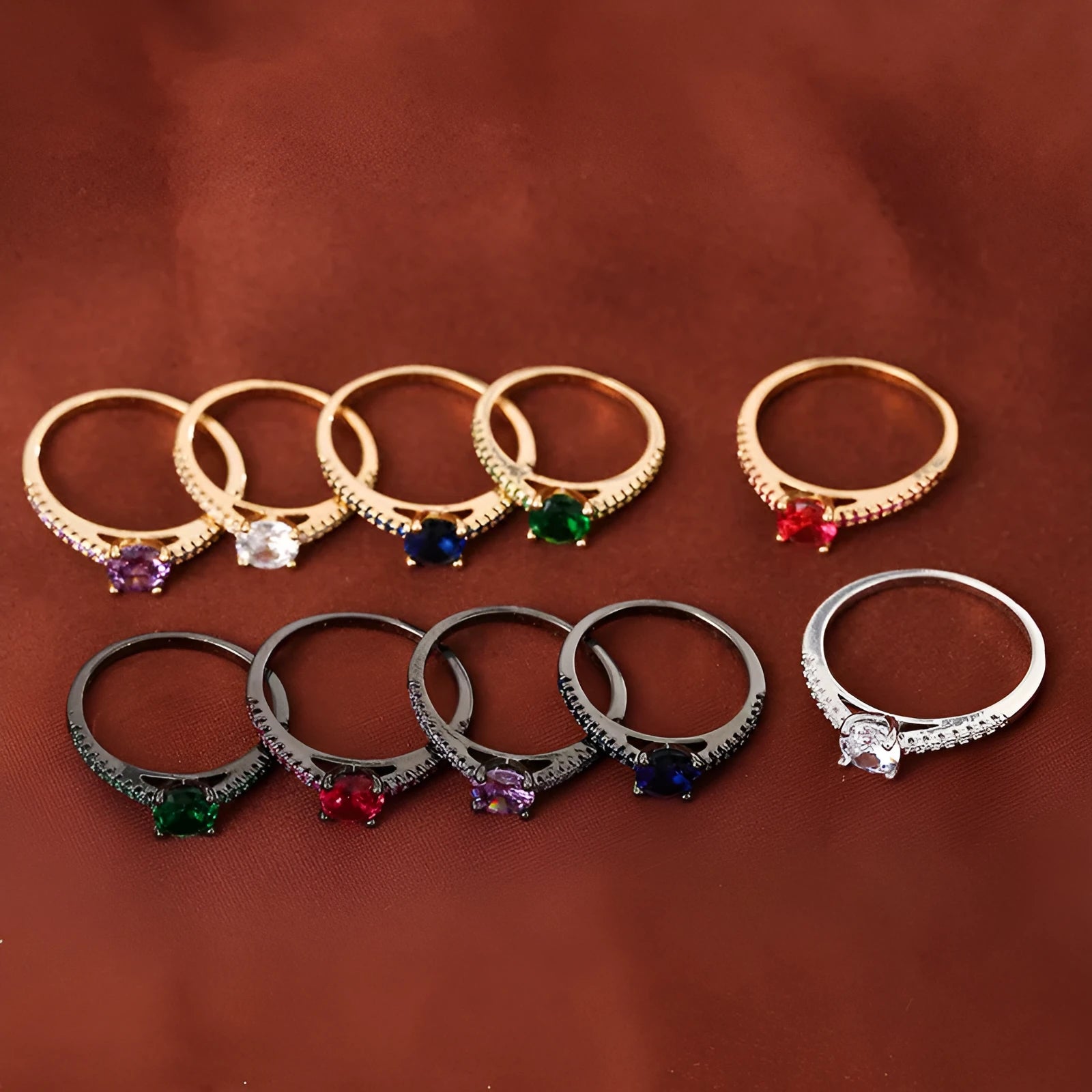 A hexagonal geometric ring with a zircon stone, shown in a gun black and rose red electroplated finish on a finger.