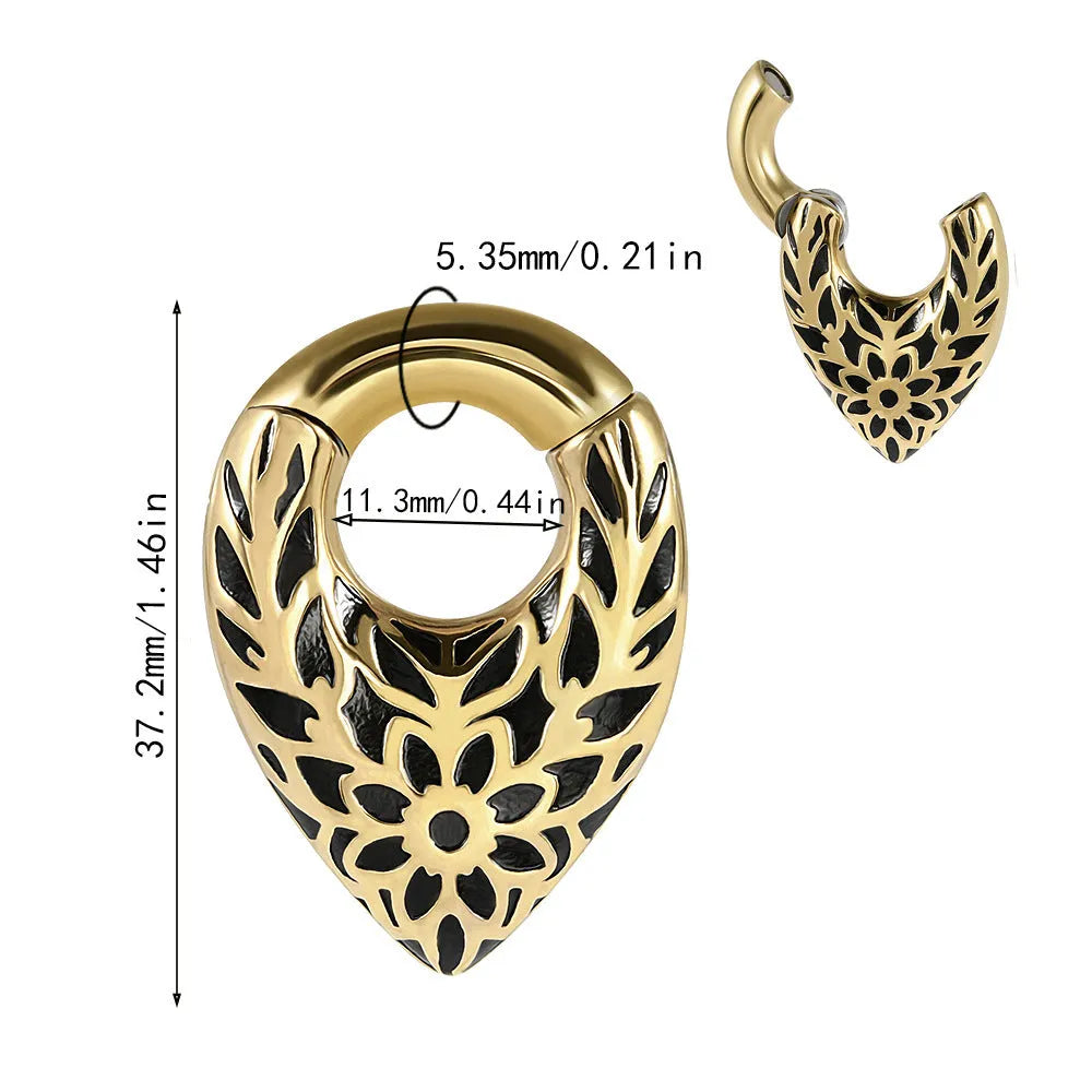 Close-up of a polished silver drop-shaped ear stretcher with a detailed totem pattern, shown against a neutral background.