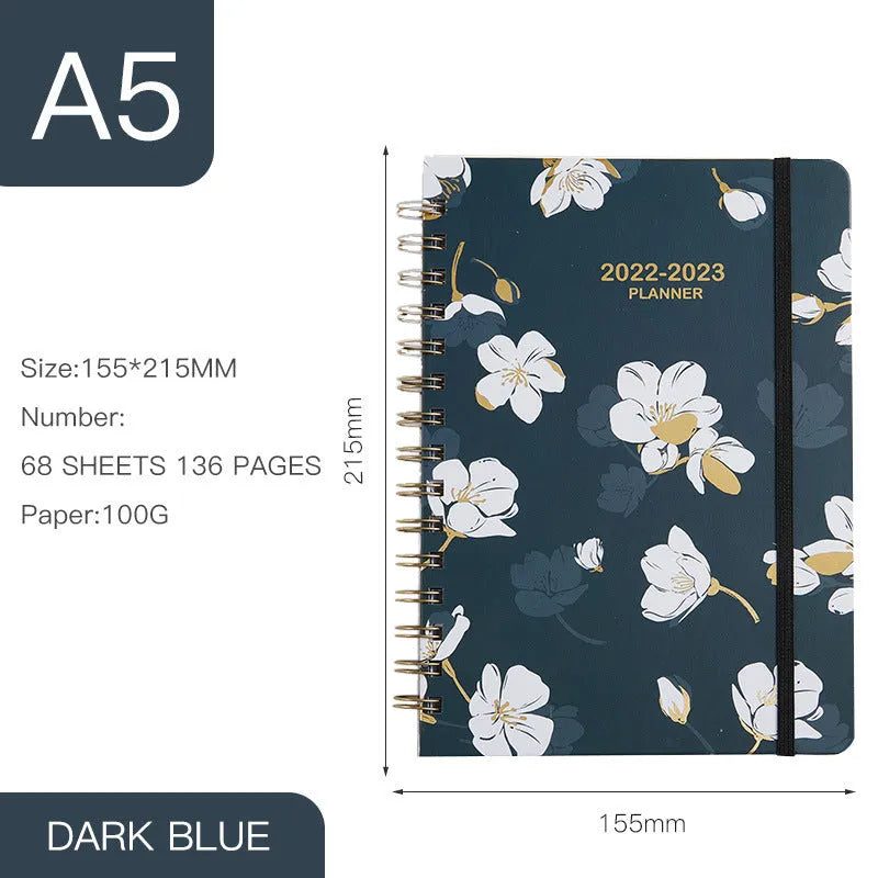 A5 spiral notebook with floral cover design, open to show lined pages.