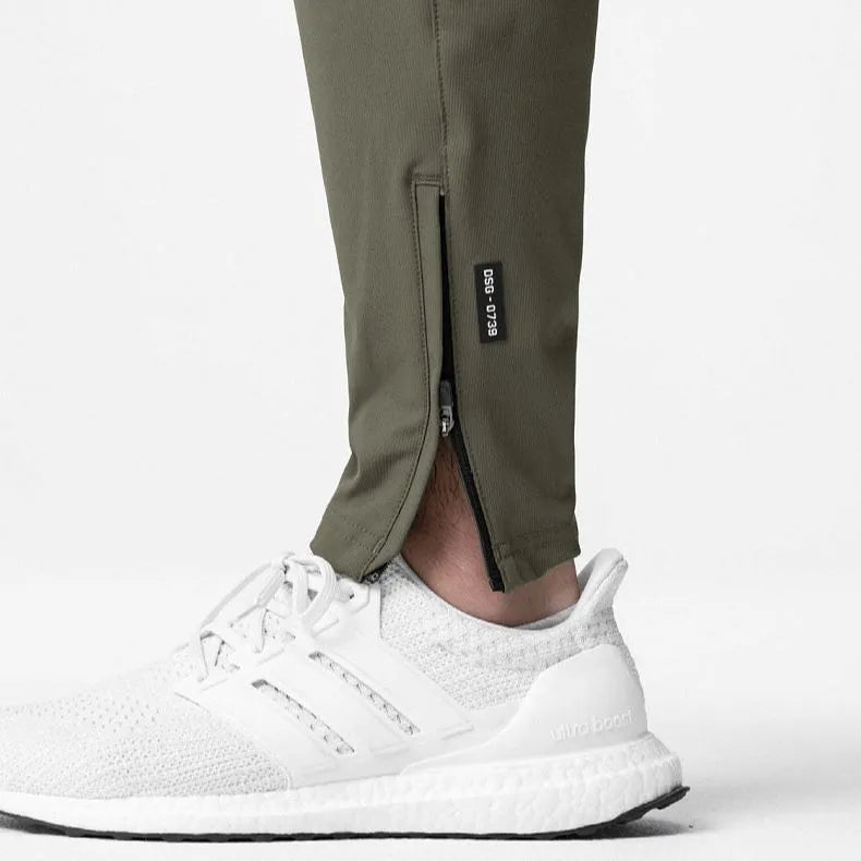 Man wearing dark grey tapered fitness trousers with adjustable ankle ties during a workout.