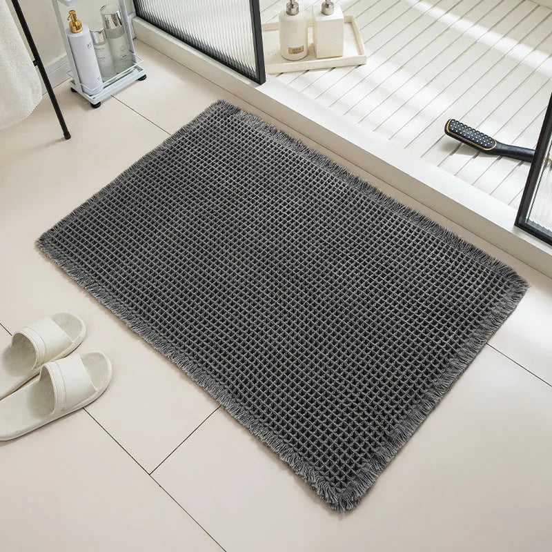 A beige checkered non-slip polyester bathroom carpet on a tiled floor.