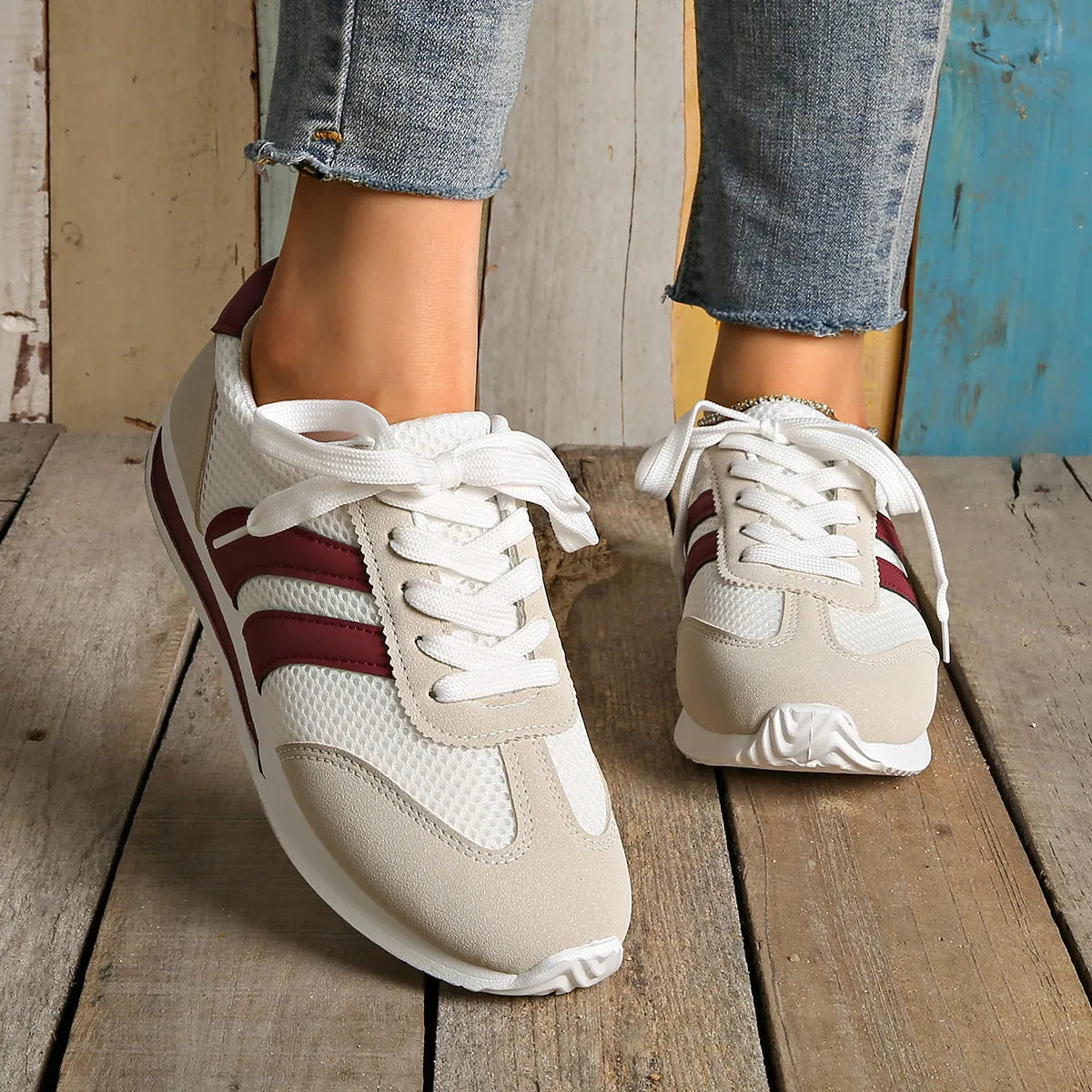 Wine red Cortez retro sneaker with cross straps, mesh lining, and flat rubber sole.