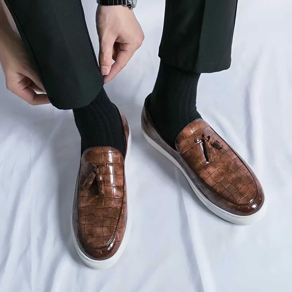 Men's black slip-on sneakers with a decorative tassel and round toe on a rubber sole.
