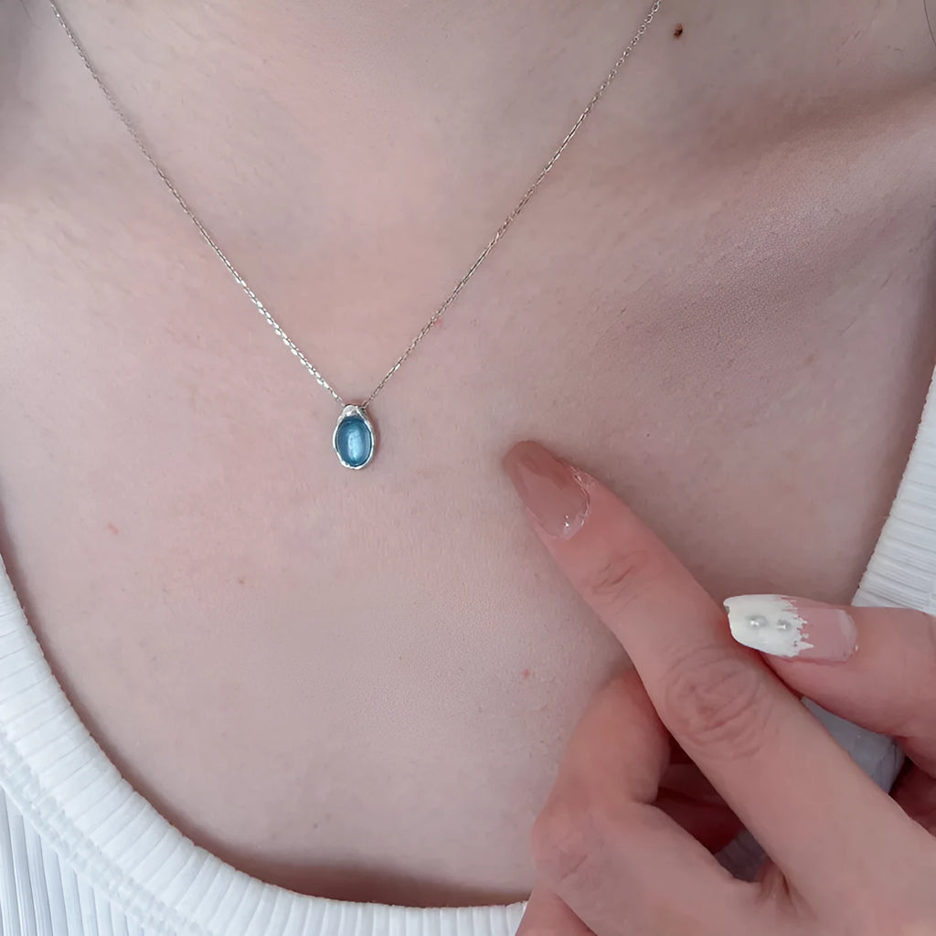 Close-up of a navy blue geometric water drop pendant on an adjustable silver-tone chain
