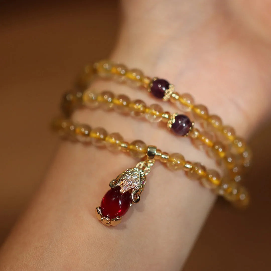 Natural Brazilian rutilated quartz bracelet with gold accents and Chinese-style charms on adjustable cord